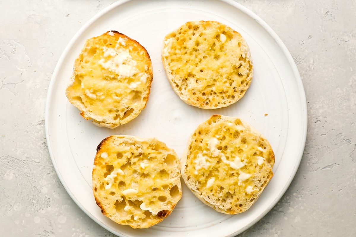 4 toasted and buttered english muffin halves on white plate