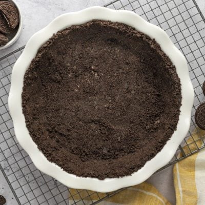 Oreo cookie crust on rack with bowl of oreos and striped napkin.
