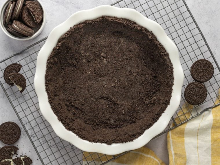 Oreo cookie crust on rack with bowl of oreos and striped napkin.