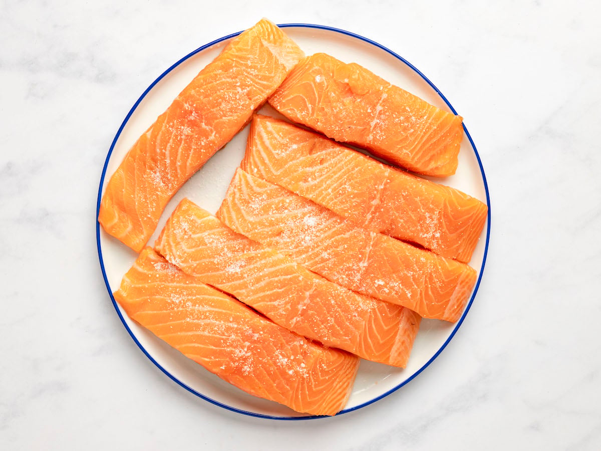 seasoned salmon fillets on white plate.