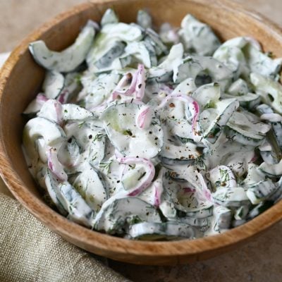 creamy cucumber salad in wooden bowl.