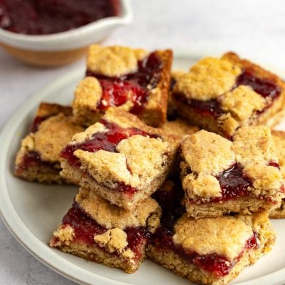 raspberry bars stacked on white platter.