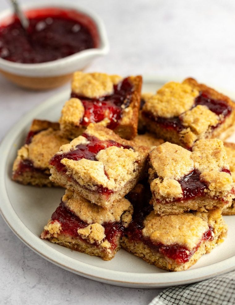 raspberry bars stacked on white platter.