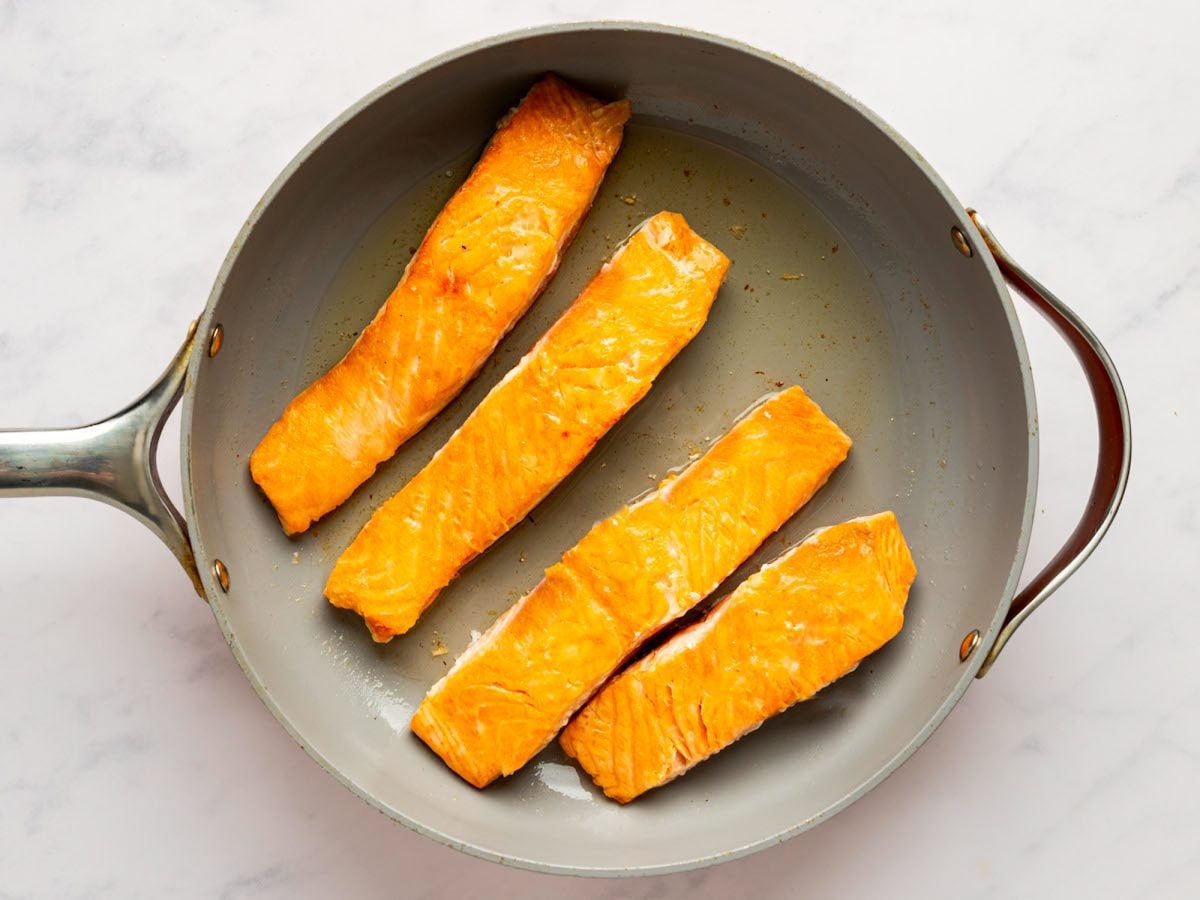 partially seared salmon fillets in pan.