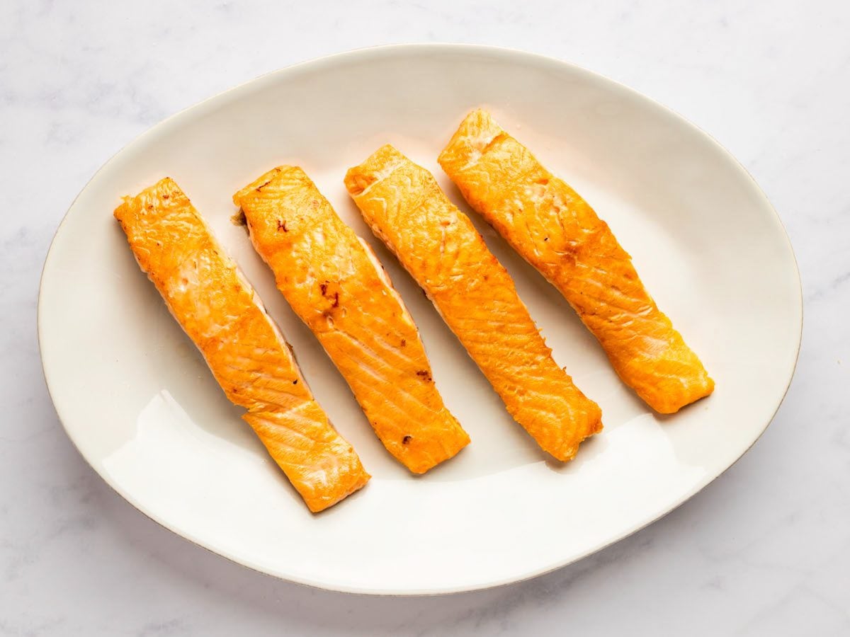 seared salmon fillets on white platter.