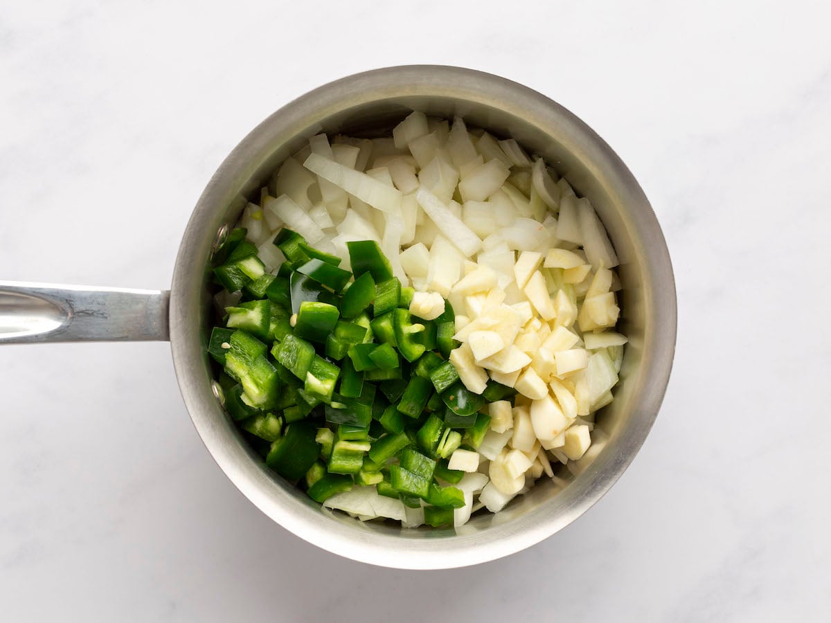 Heating the olive oil over medium heat in a small saucepan and adding the onions, garlic and jalapeño peppers.