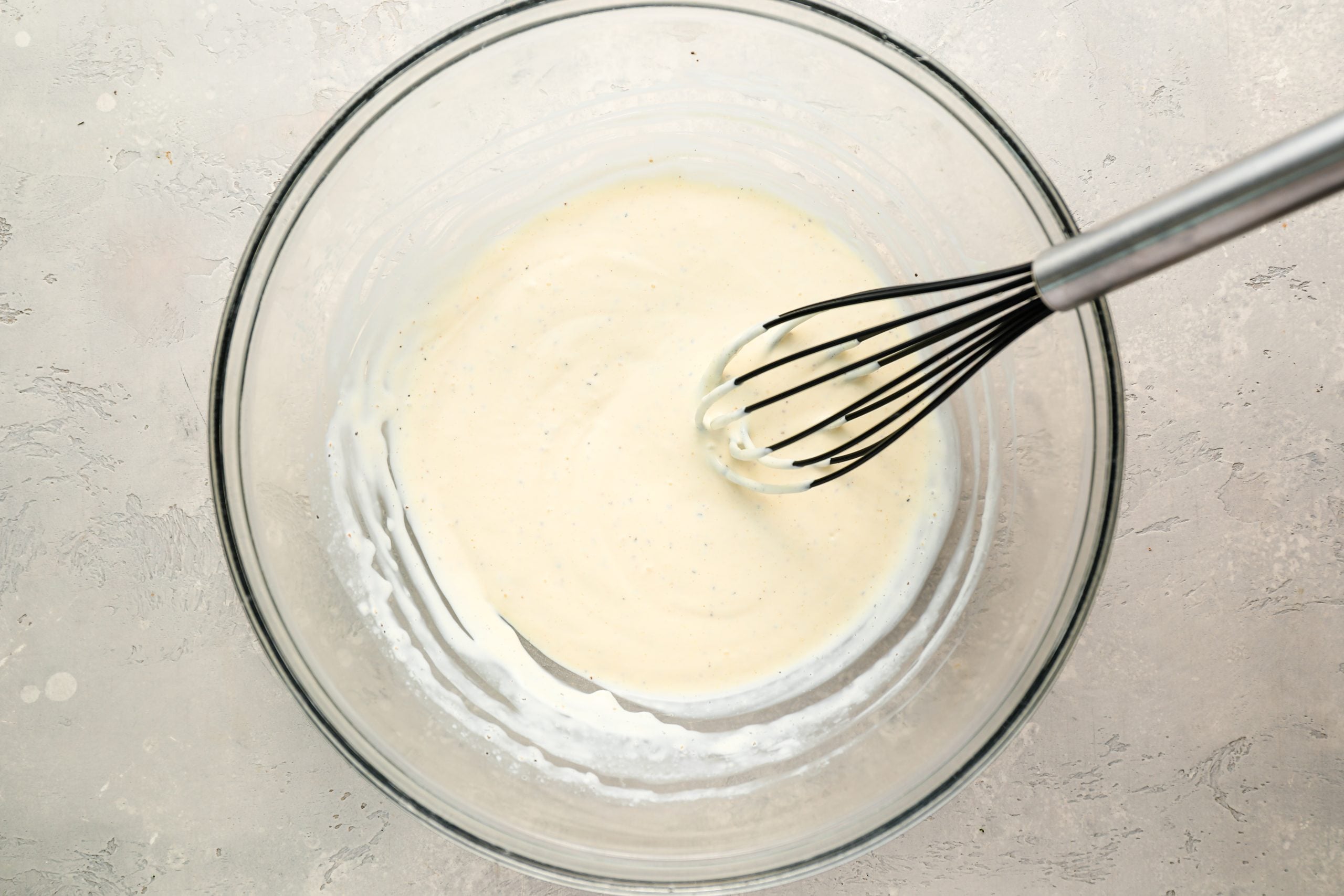 Sour cream, mayonnaise, and seasoning whisked in bowl.