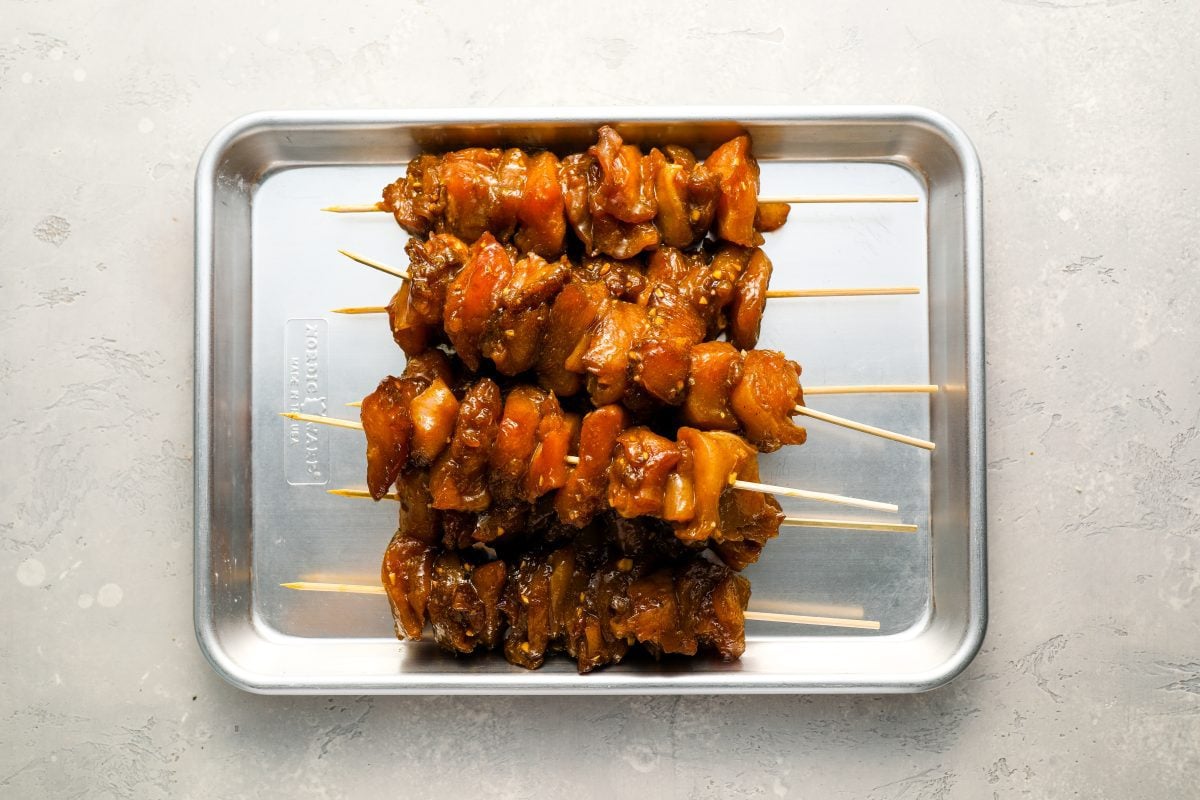 skewered chicken on baking sheet.