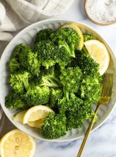 steamed broccoli in bowls with lemon wedges
