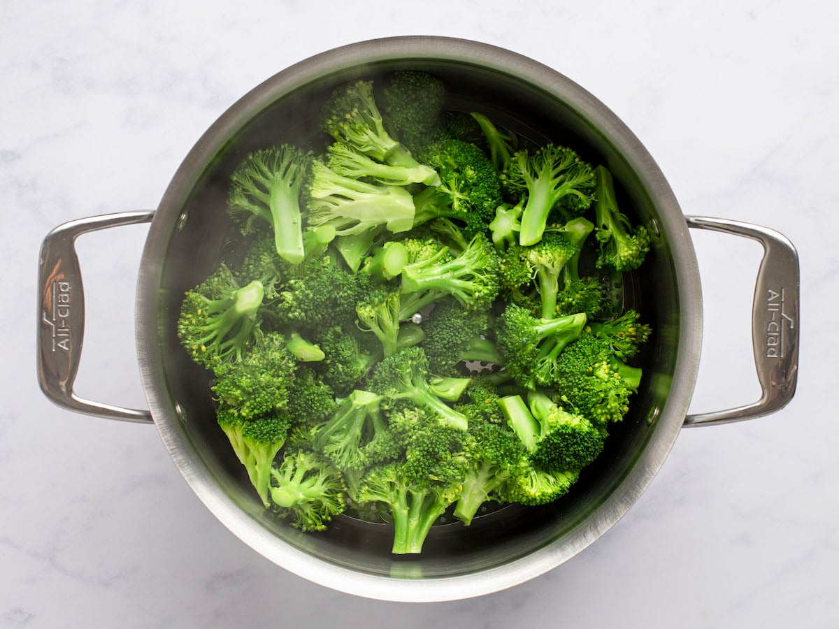 steamed broccoli in steamer basket in large pot