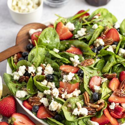 bowl of spinach salad with berries, pecans, goat cheese and raspberry vinaigrette