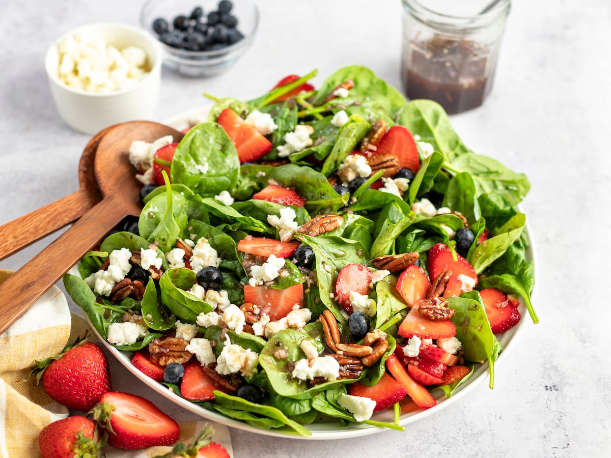 bowl of spinach salad with berries, pecans, goat cheese and raspberry vinaigrette