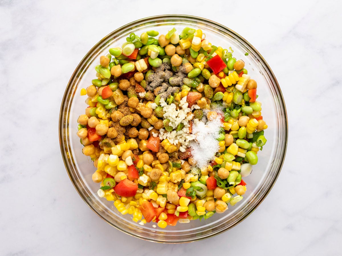 lime juice, garlic, oil, honey, salt, pepper, and cumin added chickpeas, bell pepper, corn, edamame, and scallions in large glass bowl