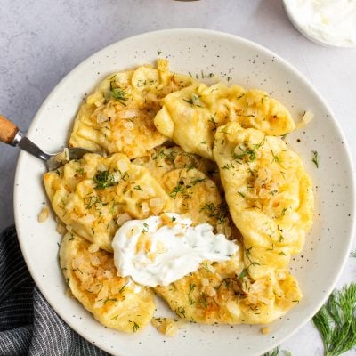 pierogi on plate with sour cream and onions