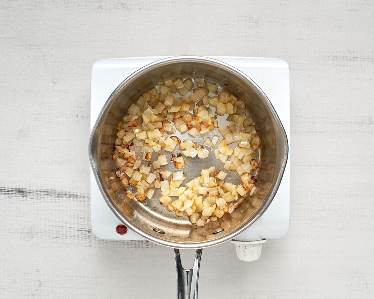 medium sauce pan with onions sauteeing in olive oil