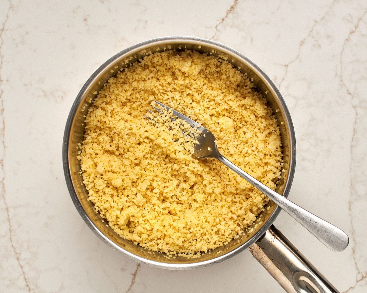 fluffing cooked couscous in medium pot
