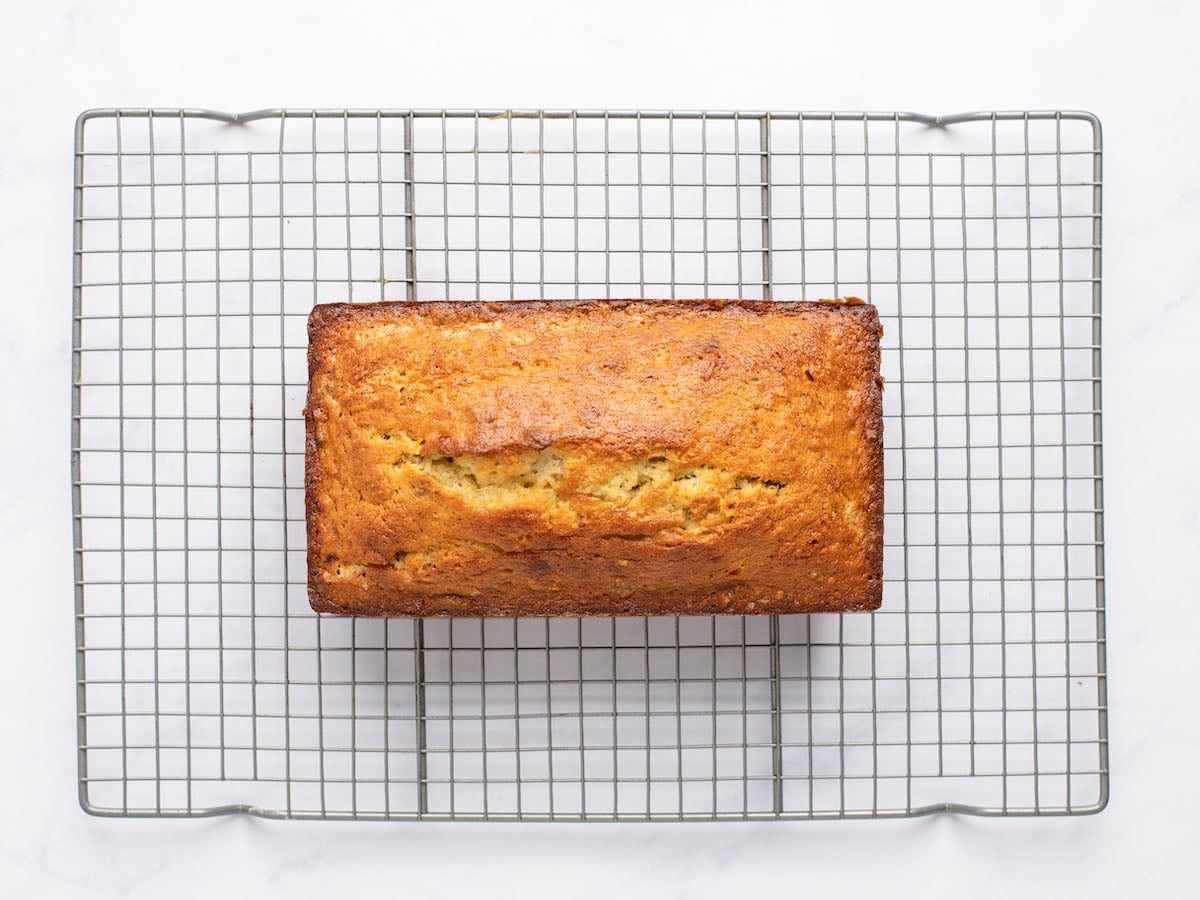 loaf of baked banana bread with coconut and pecans on cooling rack