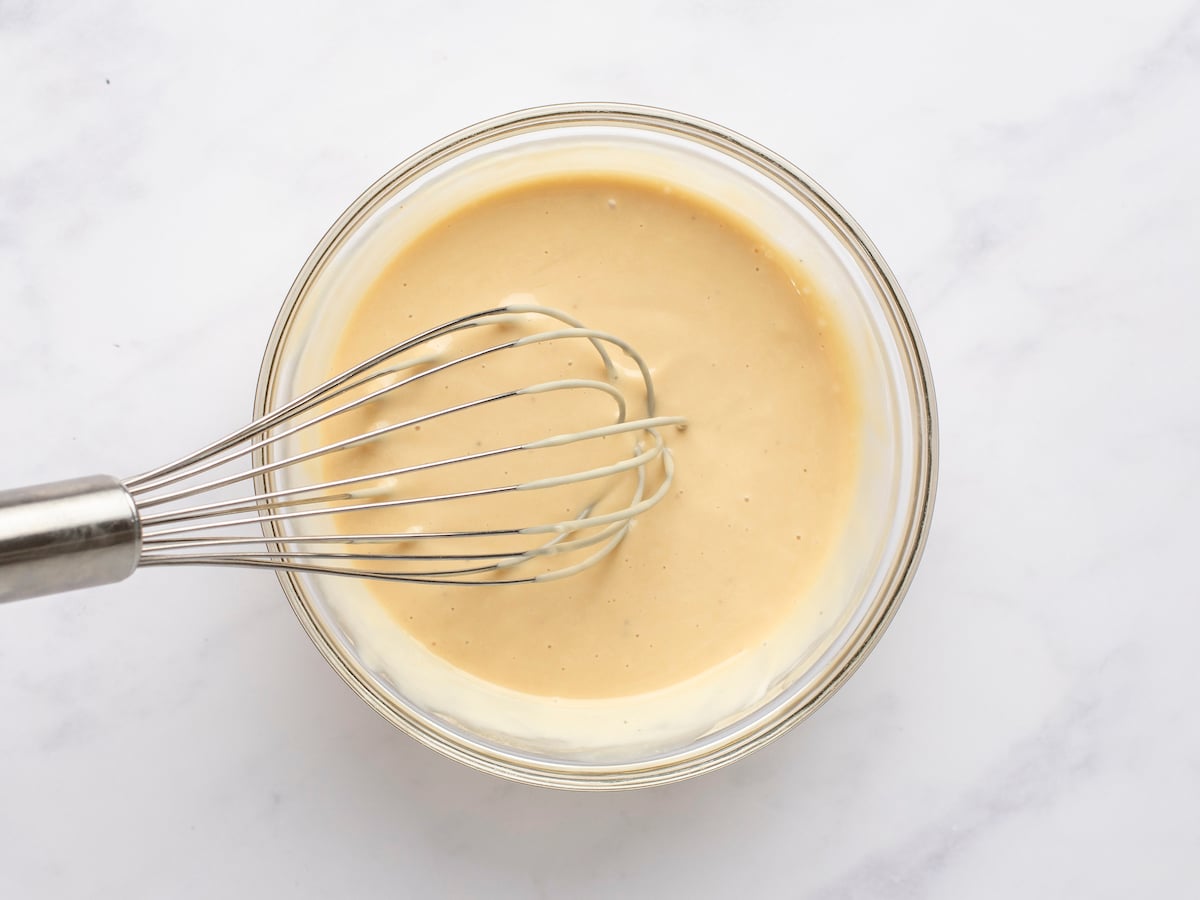 mayonnaise, mustard, black pepper, honey, and vinegar being whisked together in small bowl
