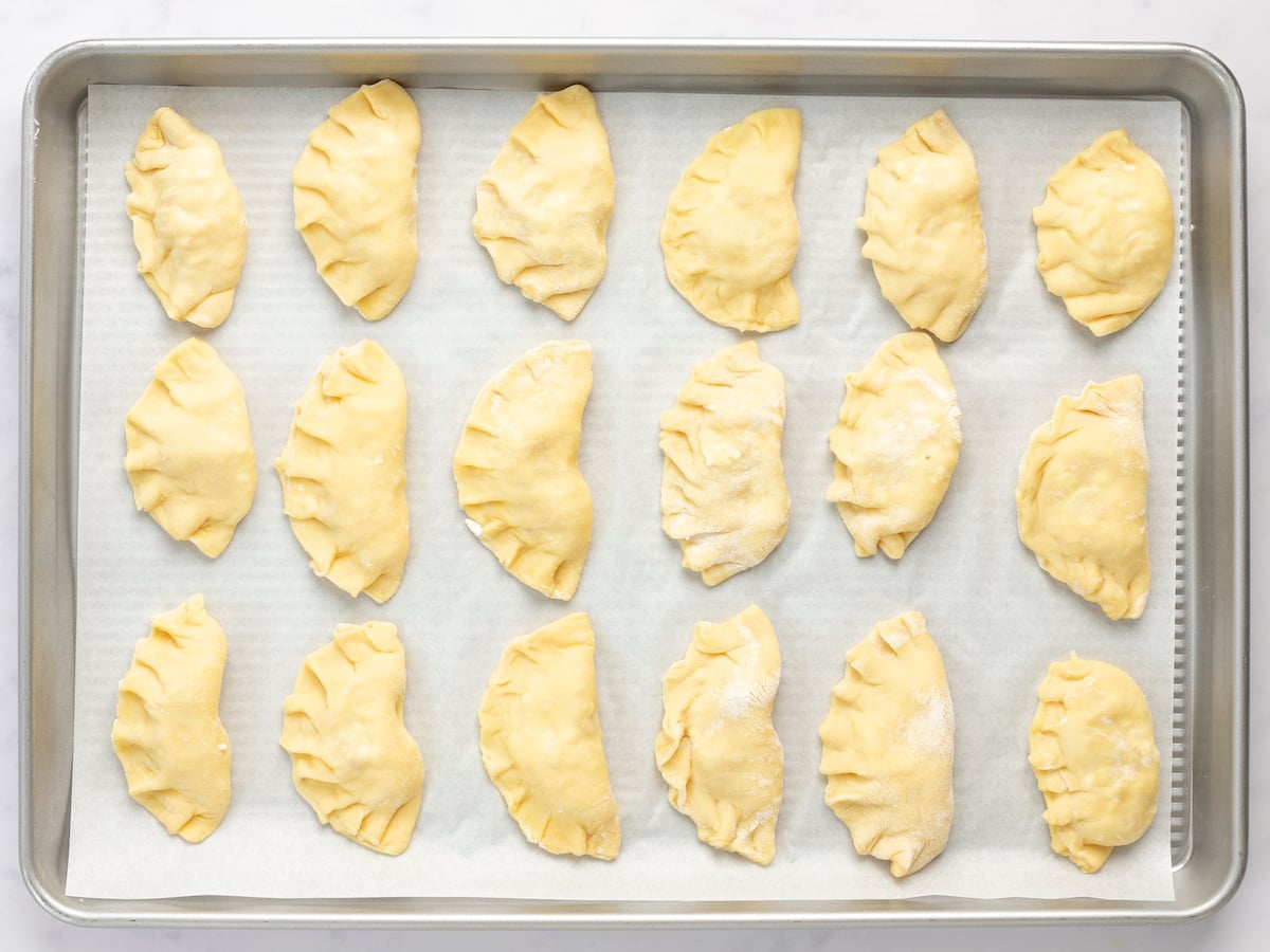 filled, folded, and sealed pierogi on baking sheet