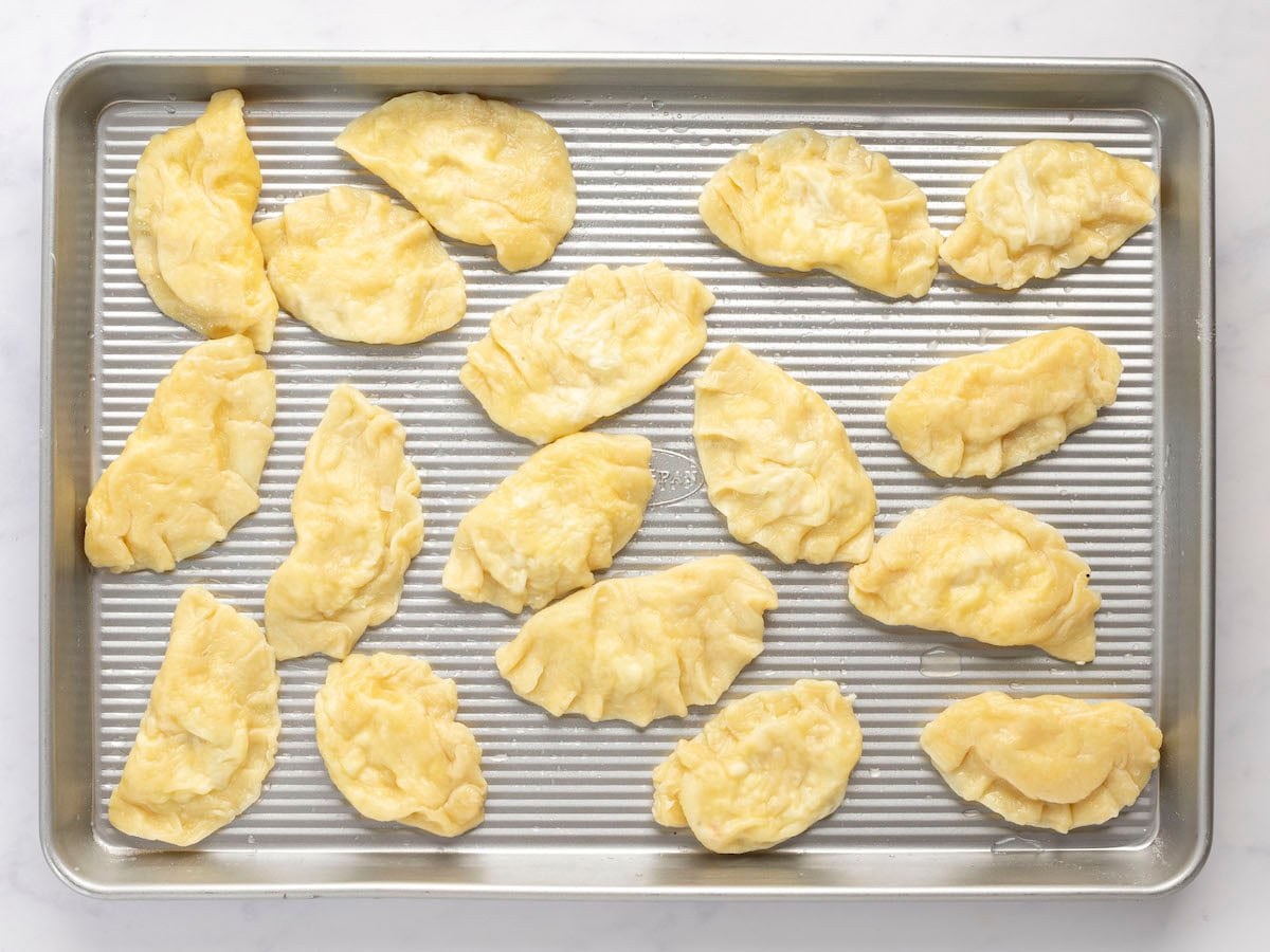 boiled pierogi with a light coating of oil on baking sheet