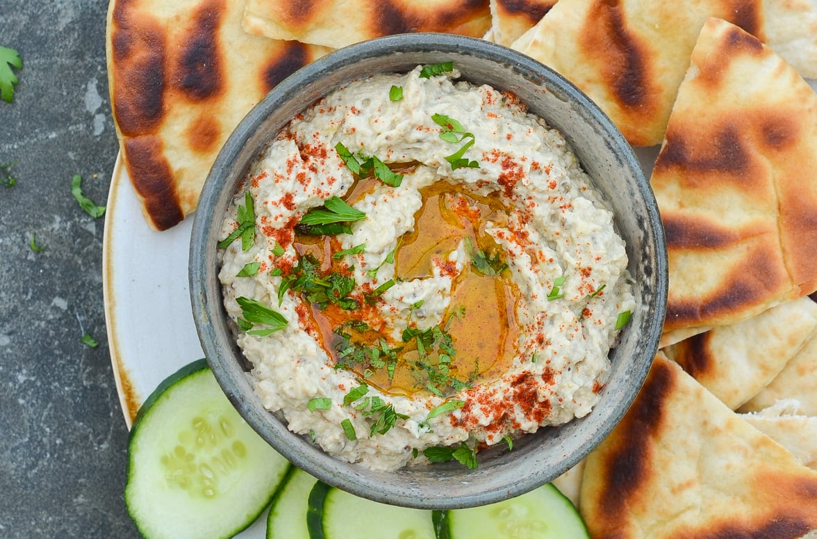 bowl of baba ganoush with cucumber slices and pita wedges