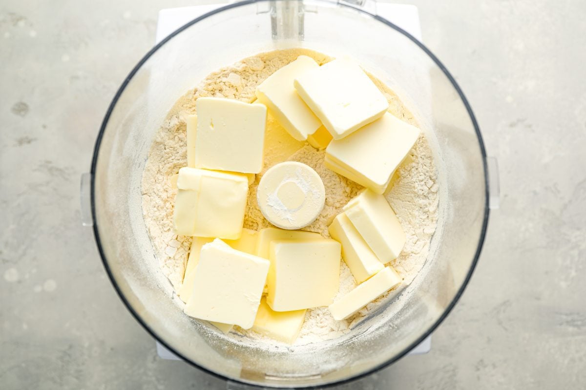 butter cubes in food processor on top of flour mixture