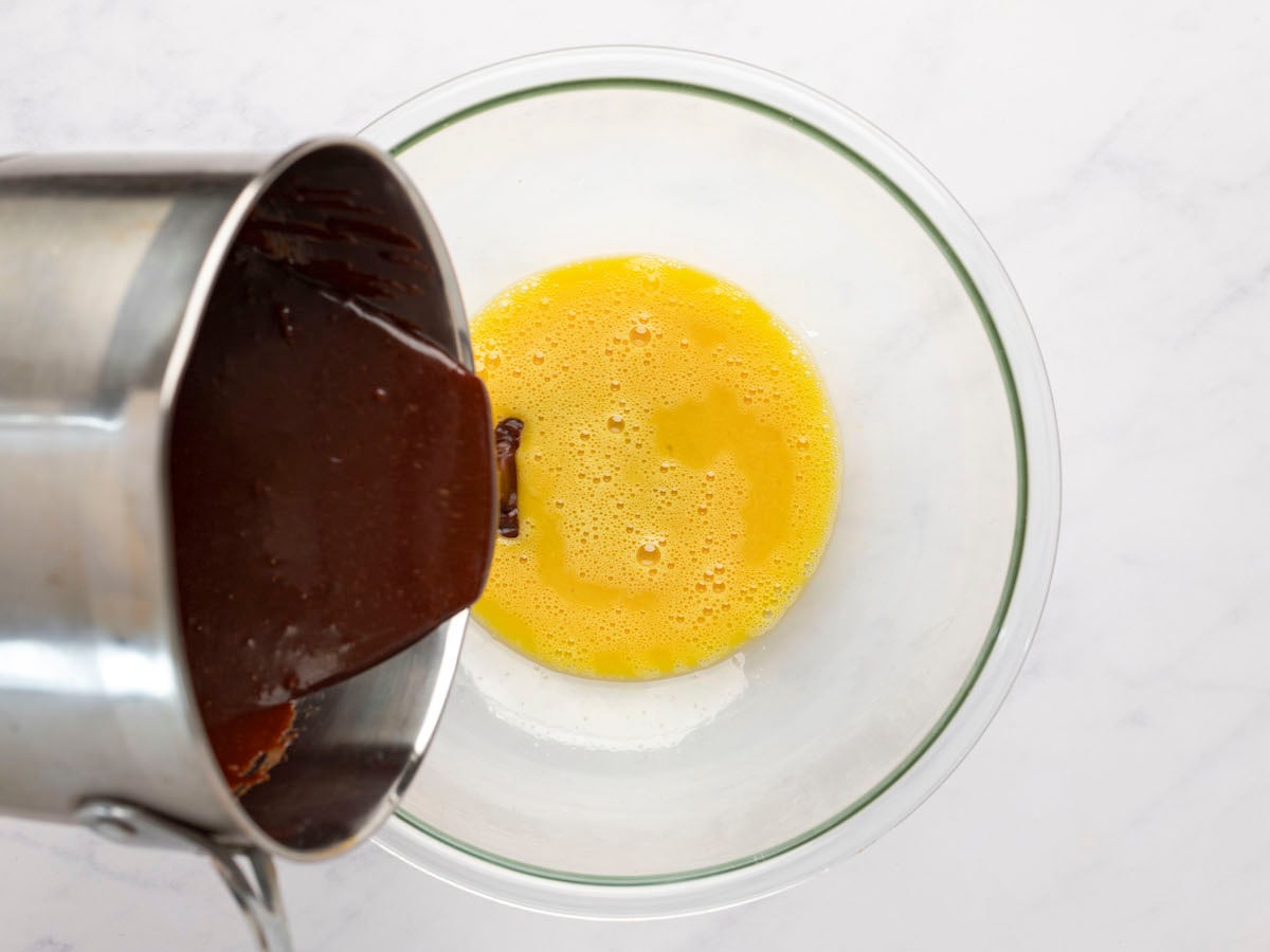 pouring chocolate mixture into large bowl with egg mixture