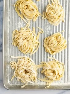 nests of homemade pasta on baking sheet.