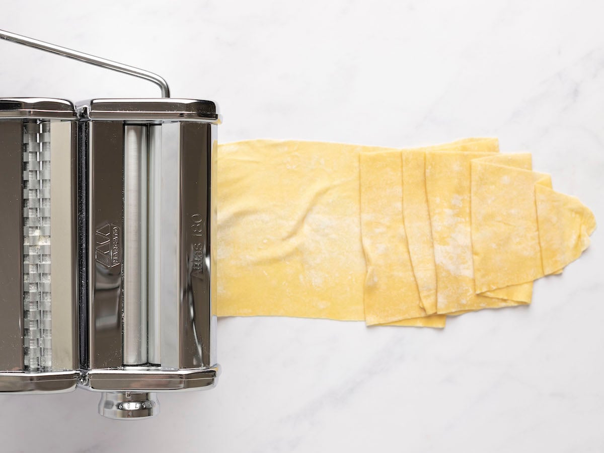 passing pasta dough through pasta machine.