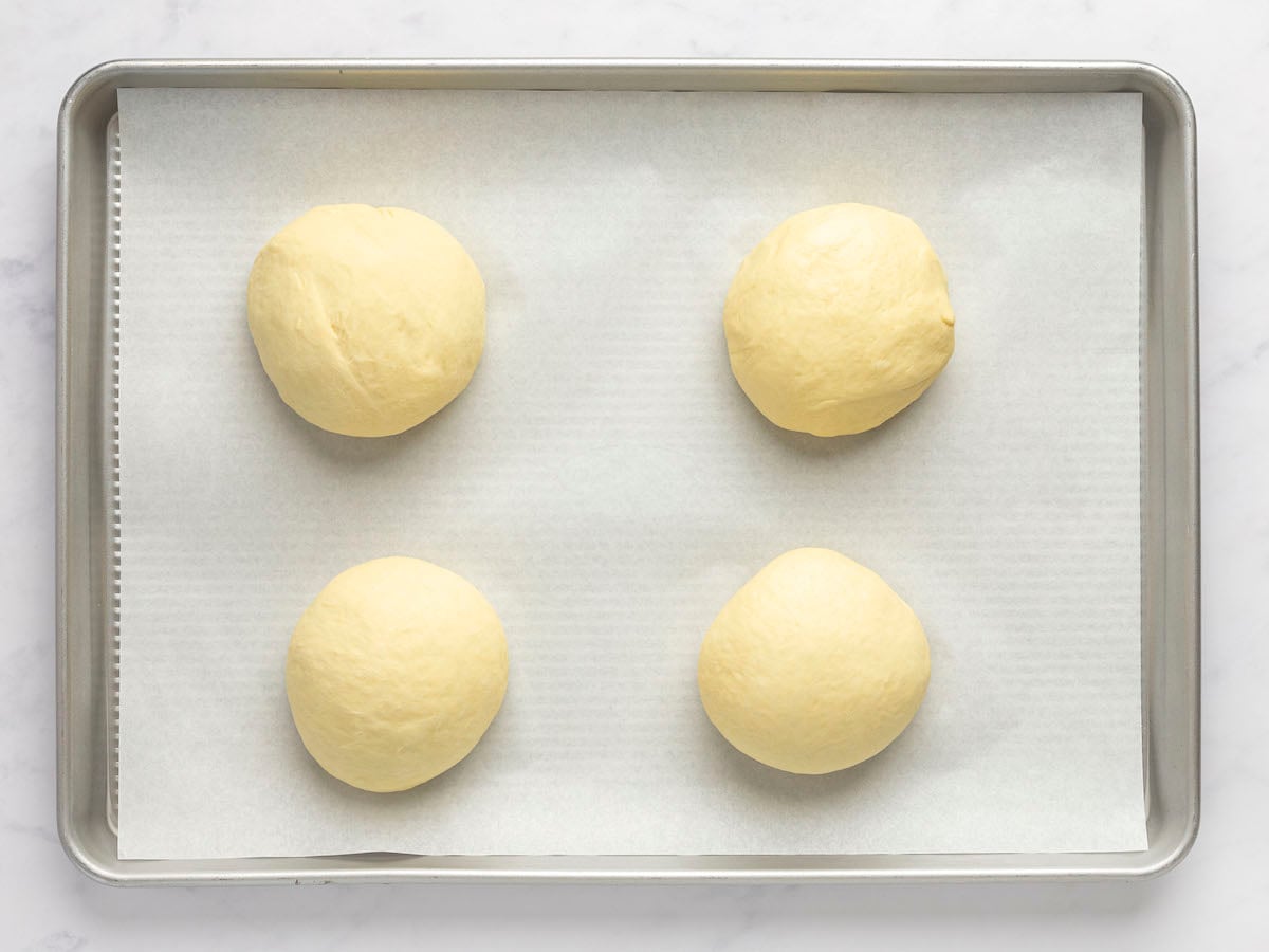 4 dough balls on parchment-lined baking sheet