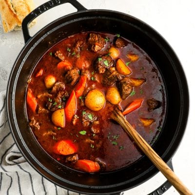 Hungarian goulash in Dutch oven with crusty bread and bowl of parsley