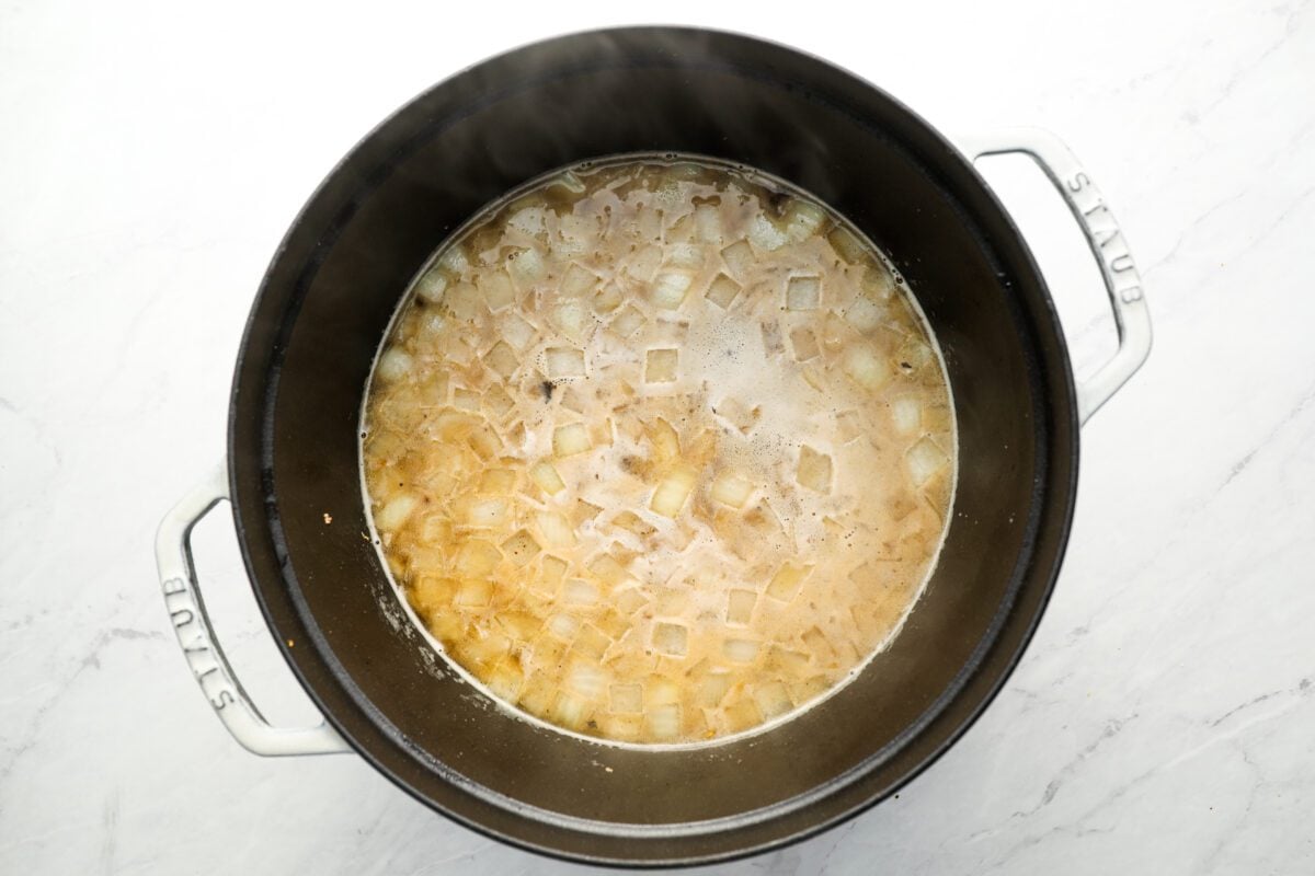 dutch oven with onions, garlic, and chicken broth