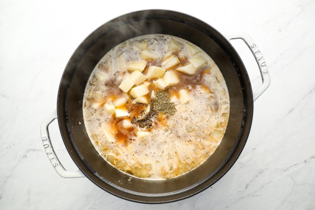 potatoes, salt, pepper, and thyme added to dutch oven with onion, garlic and chicken broth