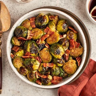 roasted Brussels sprouts with bacon in bowl with serving spoon and linen napkin