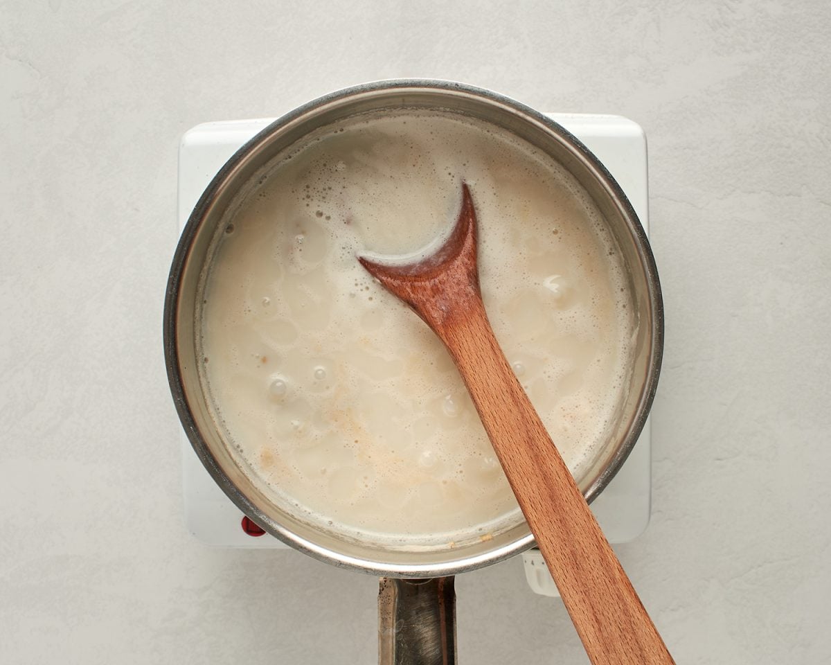 partially cooked steel cut oats in pot with wooden spoon