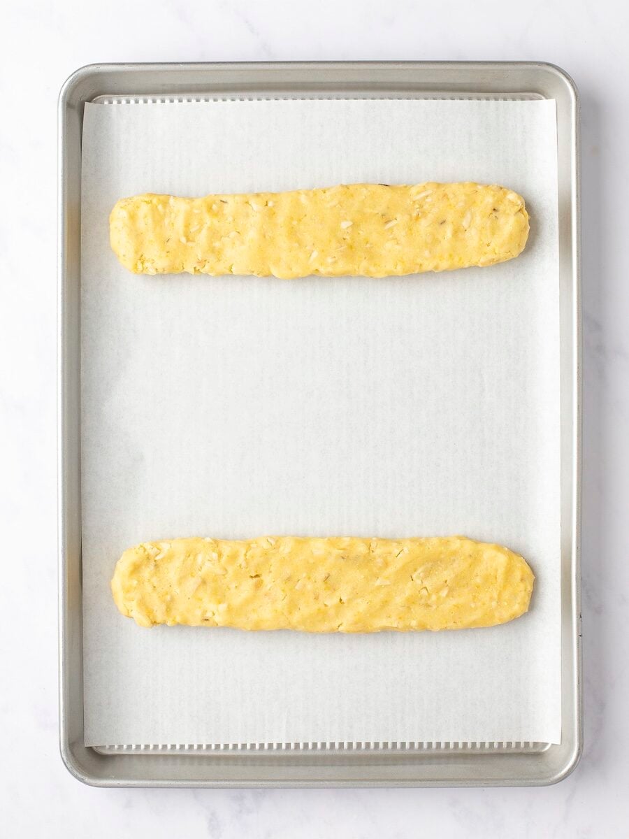 Biscotti dough logs formed on parchment-lined baking sheet.
