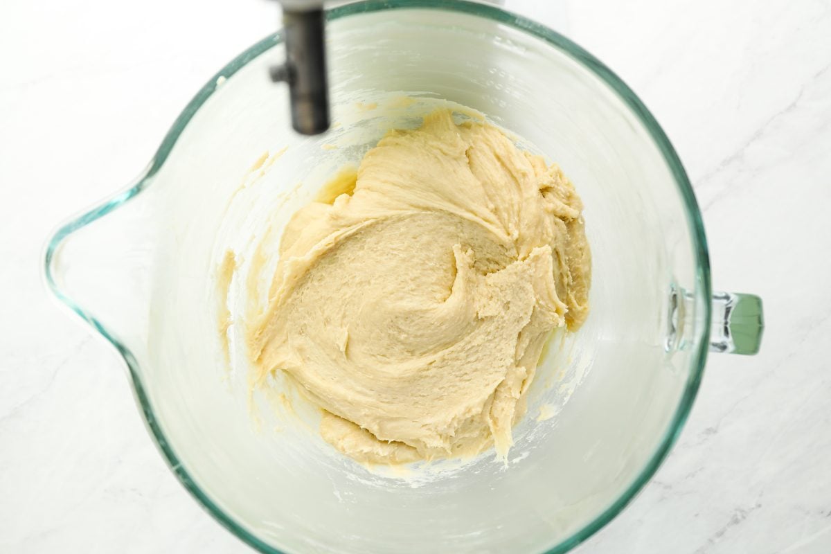 glass bowl with milk, eggs, and egg yolk combined with flour mixture to form dough