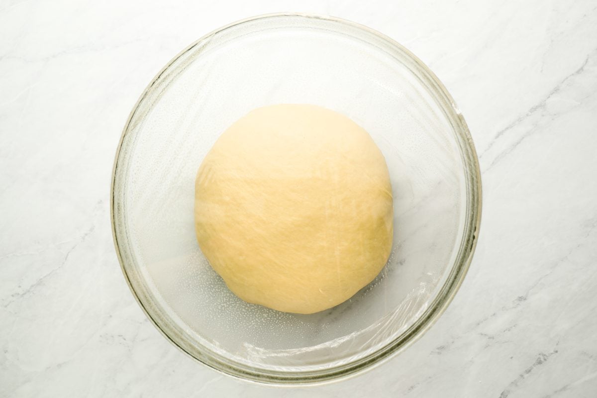 dough in large glass bowl covered with plastic wrap