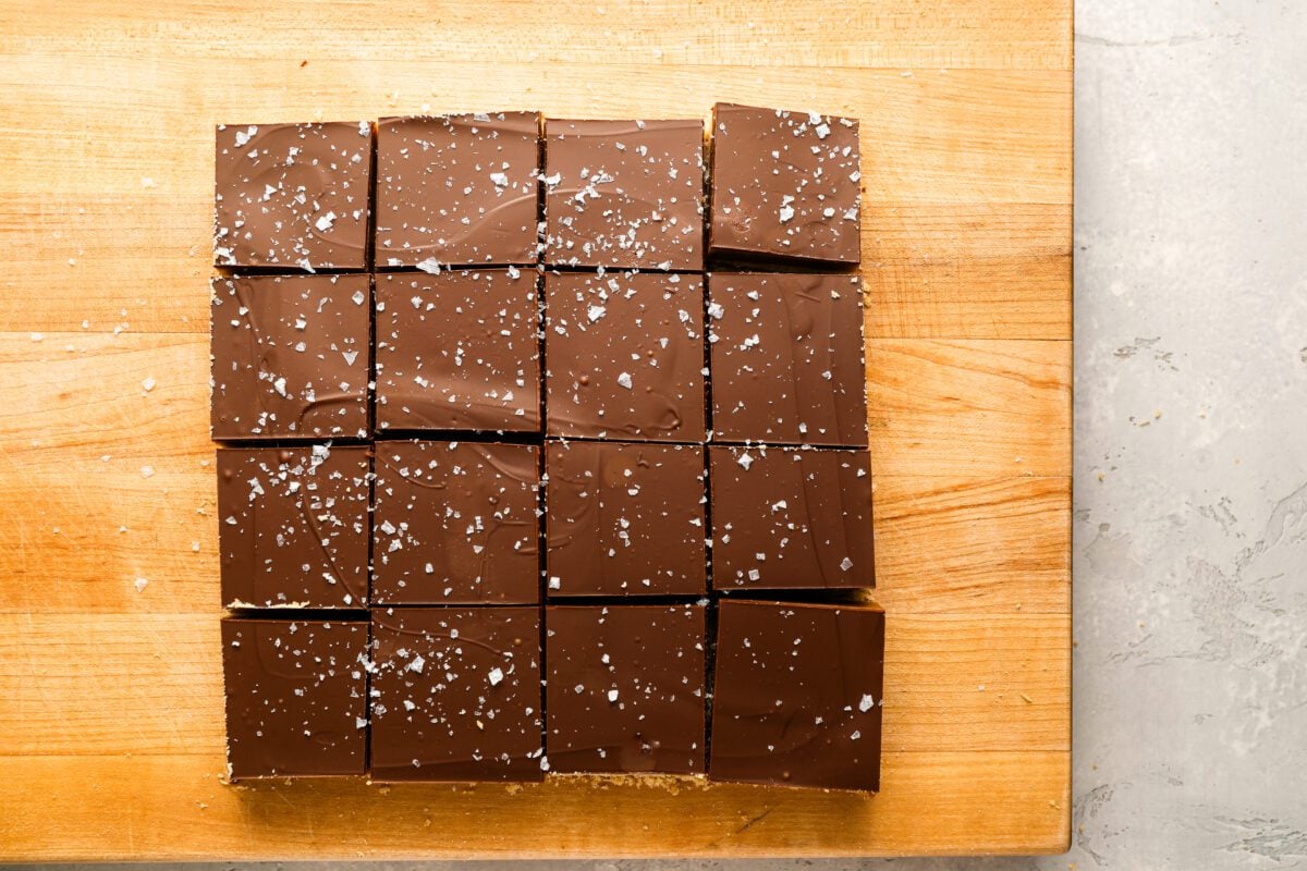 millionaire's shortbread bars on cutting board sprinkled with flaky sea salt.