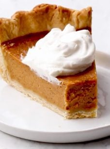 Slice of pumpkin pie on a plate with a fork.