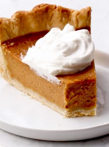 Slice of pumpkin pie on a plate with a fork.
