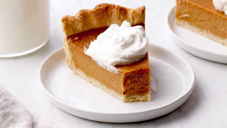 Slice of pumpkin pie on a plate with a fork.