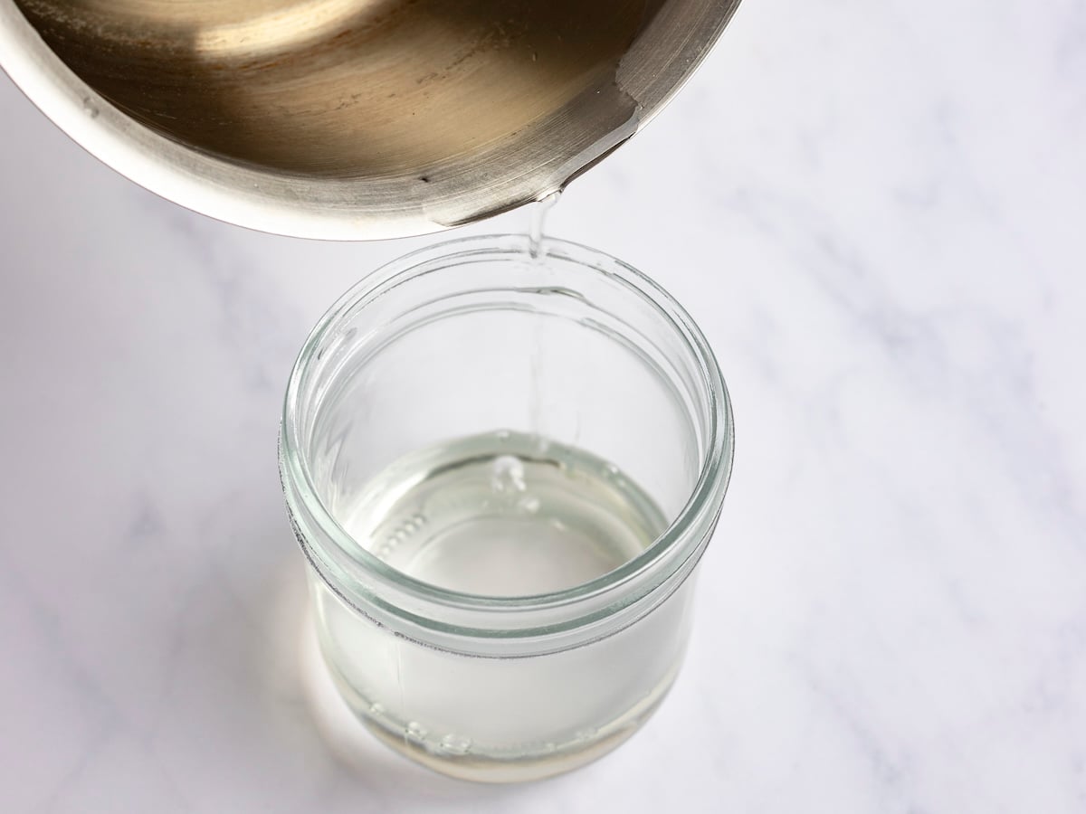 pouring simple syrup into a jar.