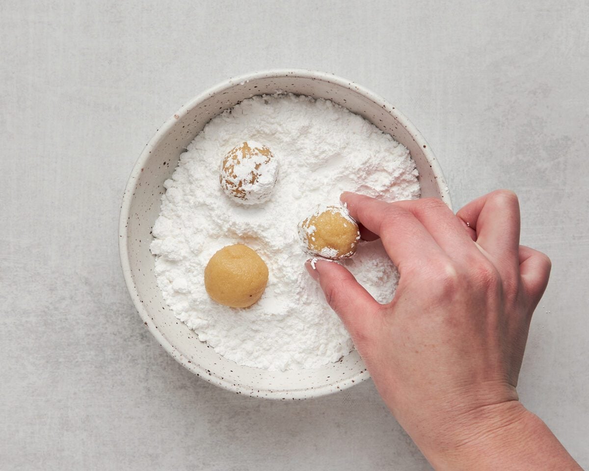 rolling almond cookie dough balls in confectioners' flour