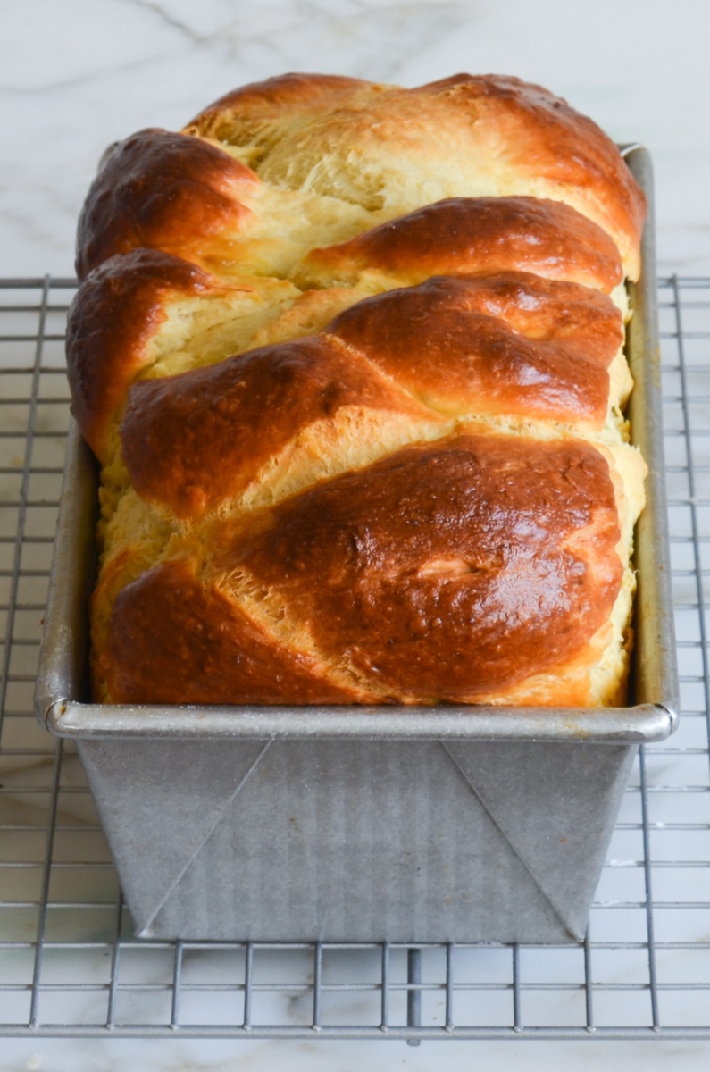brioche cooling on rack in loaf pan.