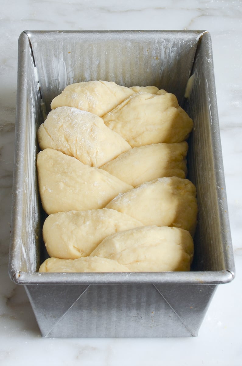 braided brioche dough in loaf pan.