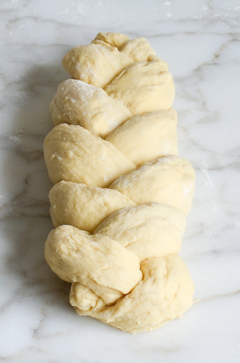 braided brioche dough on marble surface.