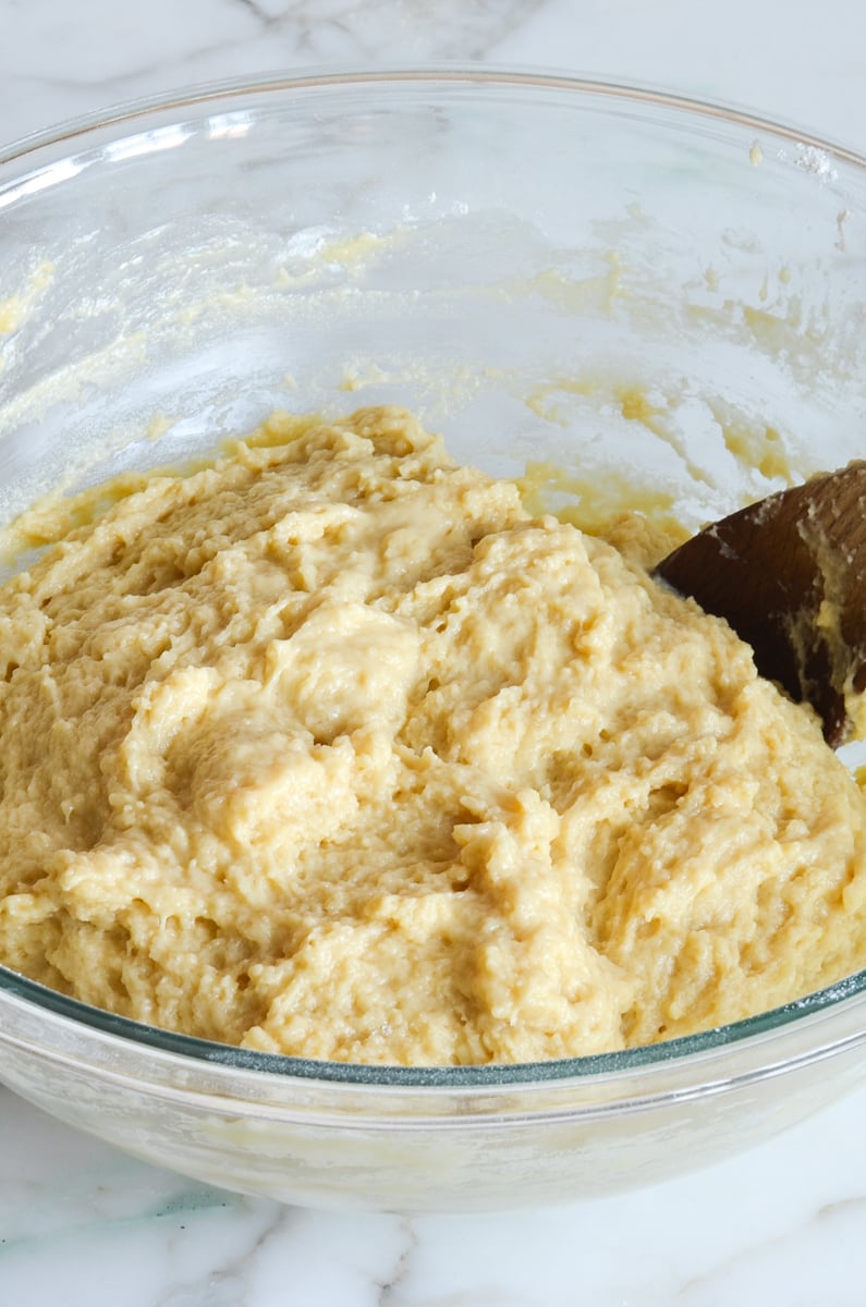 brioche dough in mixing bowl with wooden spoon.