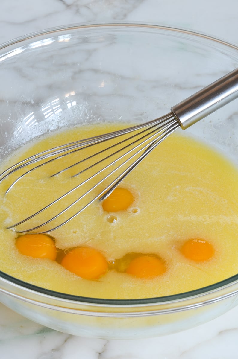 eggs added to liquid ingredients in mixing bowl with whisk.