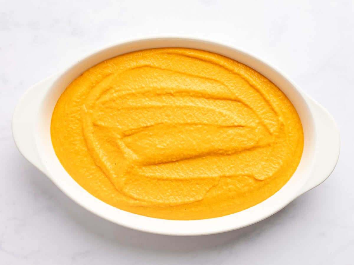 uncooked souffle spread evenly in white oval baking dish